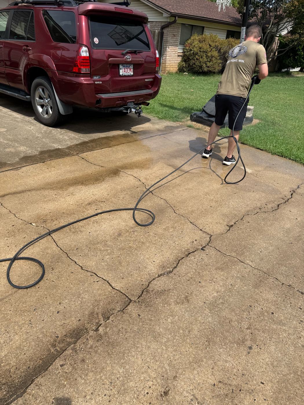 Pressure washing a Fort Smith driveway — clean path cut through stained concrete