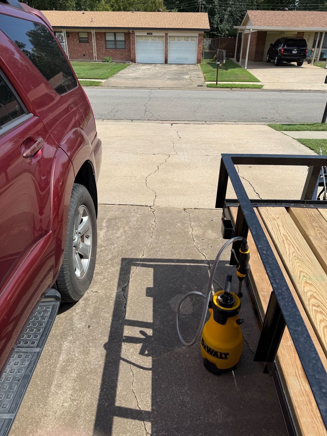 Yellow DeWalt sprayer on a driveway during a pressure washing job